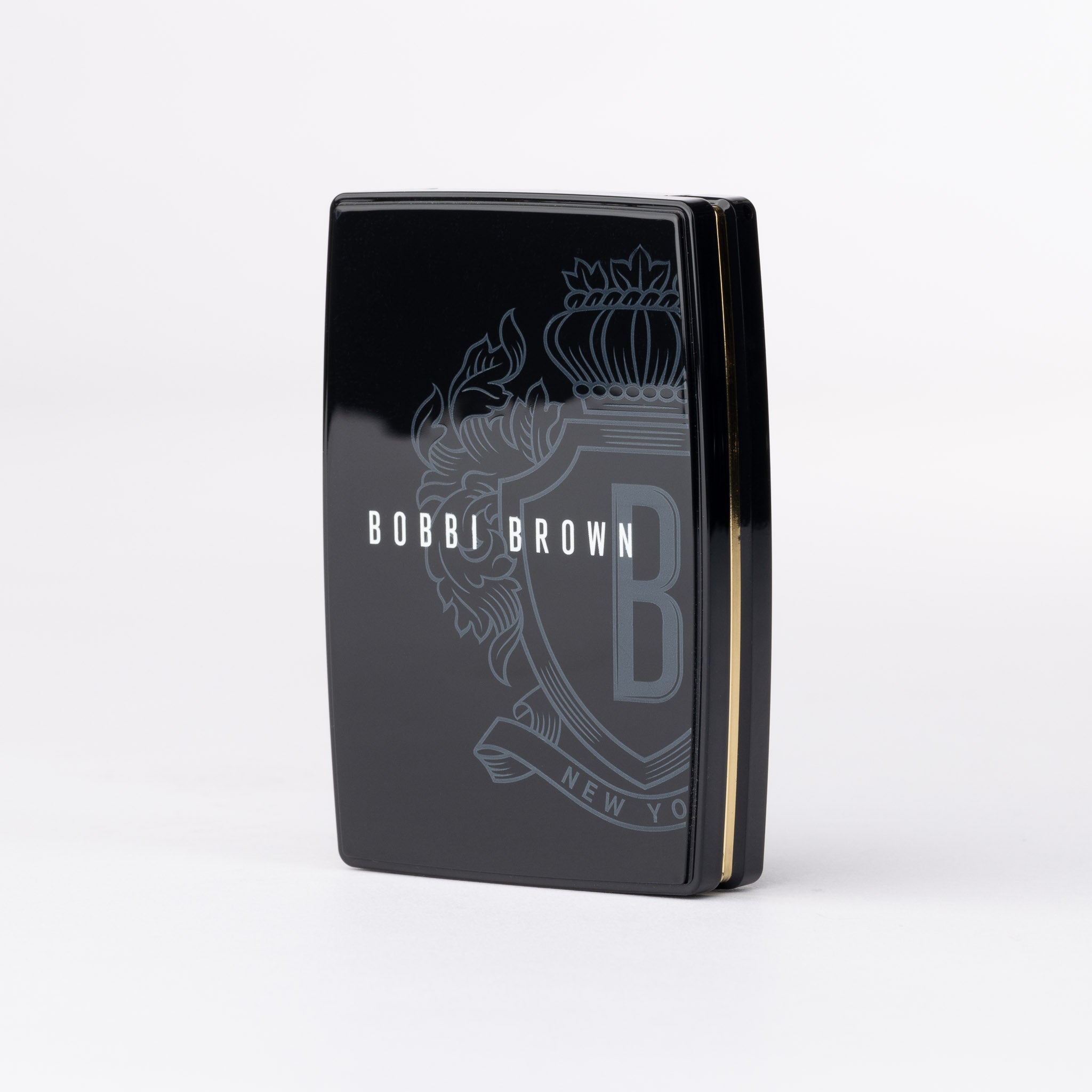 Bobbi Brown glossy black compact with gold trim and grey crest design.