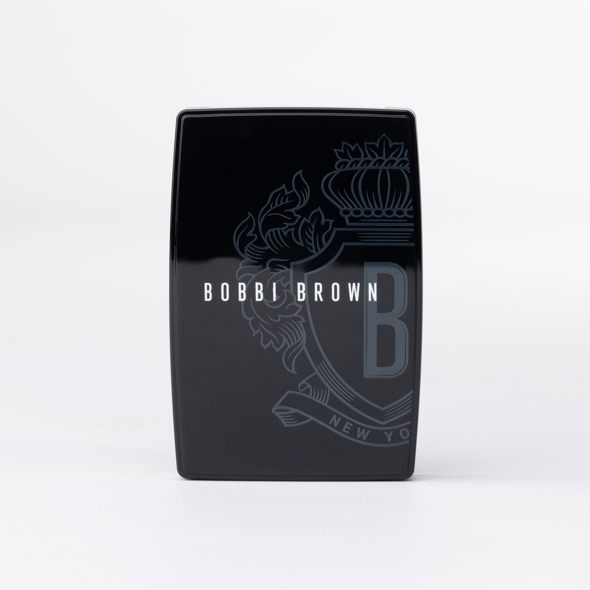 Bobbi Brown black sleek compact, featuring an ornate crest with 'B' monogram and 'New York' details in grey.