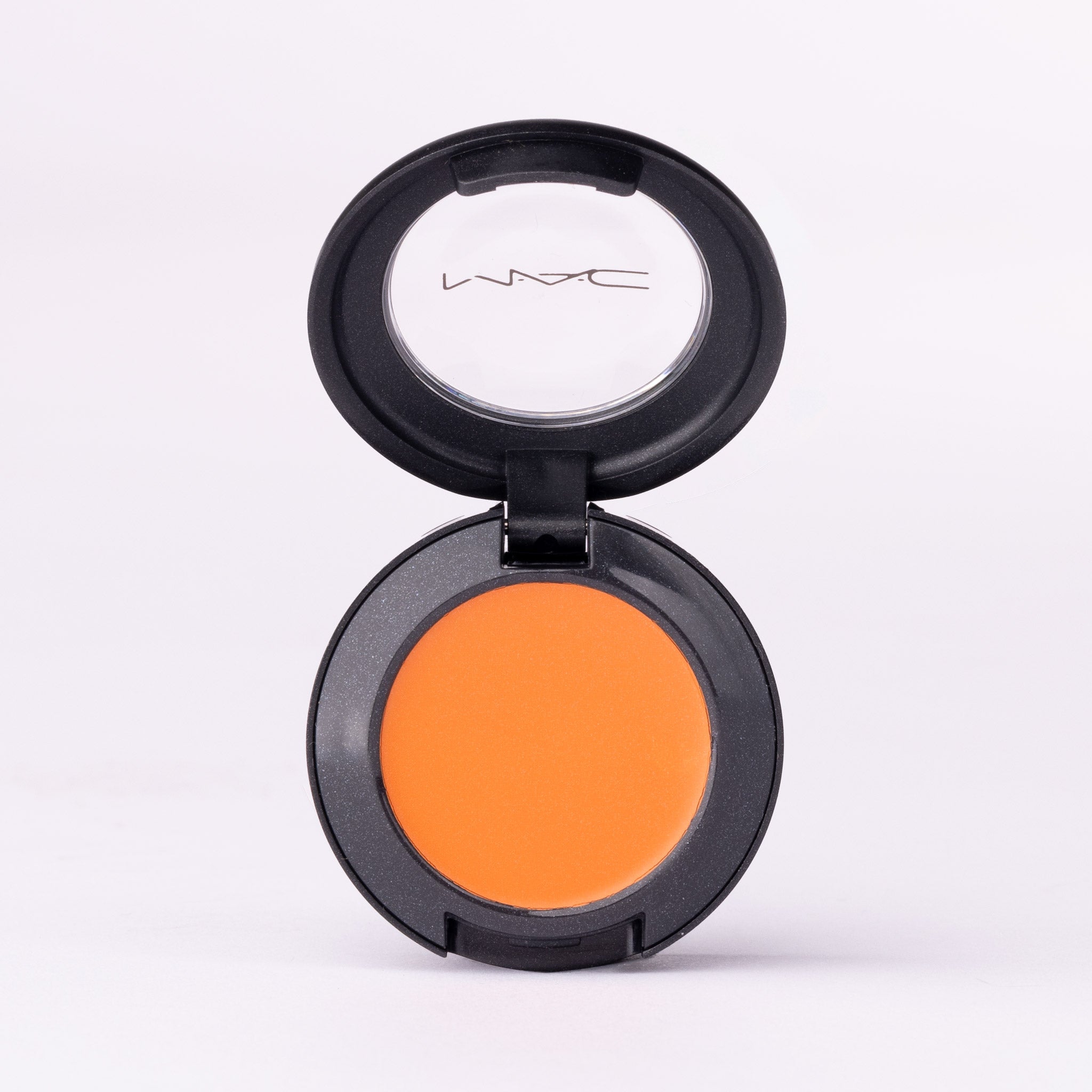 MAC vibrant orange creamy eye shadow, open black compact, clear logo lid.