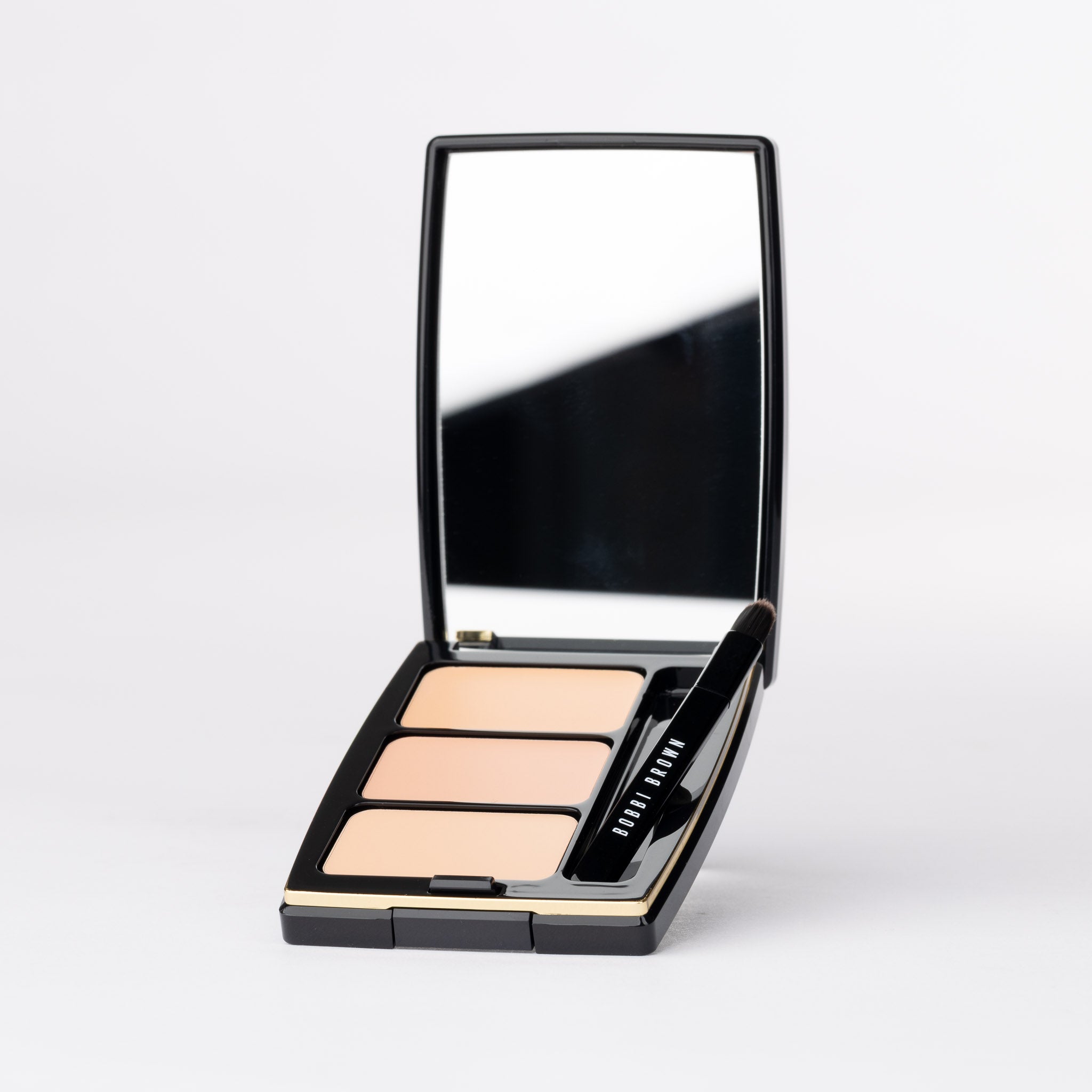 Bobbi Brown luxurious face palette open: 3 creamy beige complexion shades, brush & mirror. Black & gold compact.